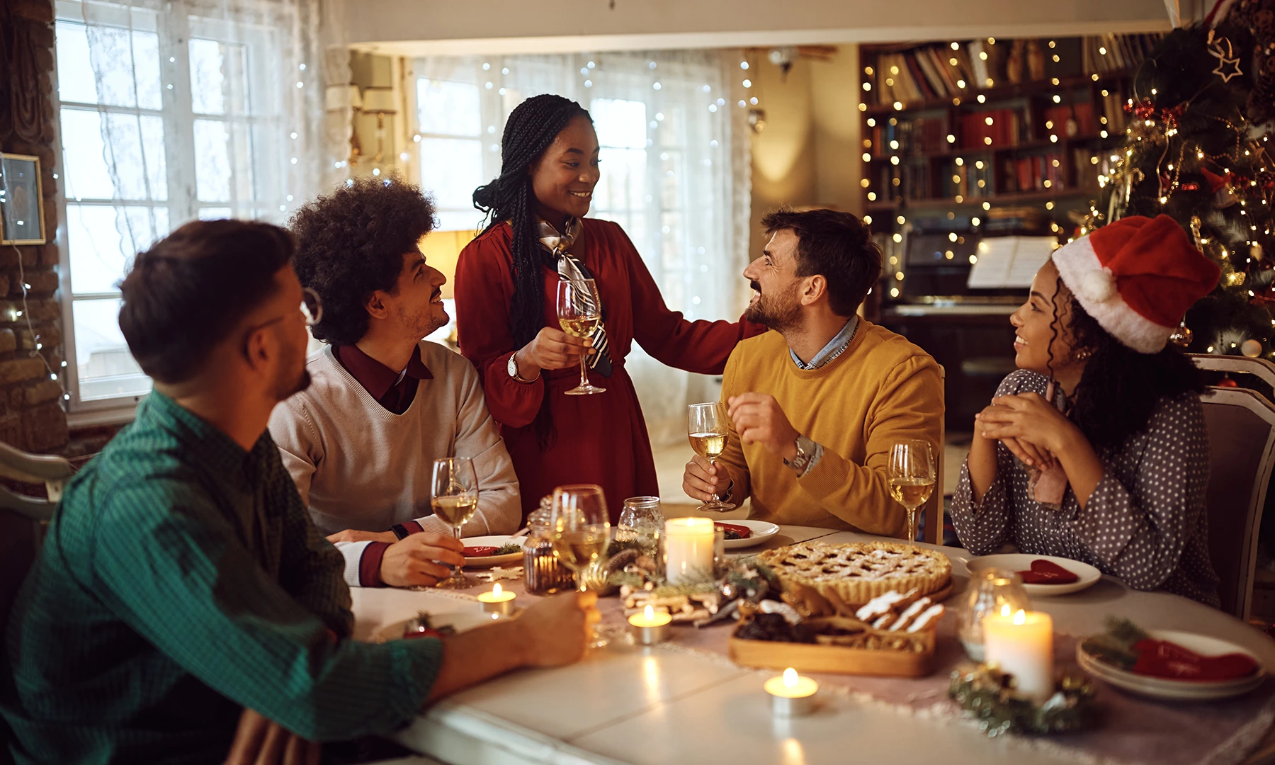 Group of people enjoying a dinner together, seated in a festively decorated home