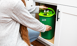 Woman putting Rinse 'n Wring under sink cabinet