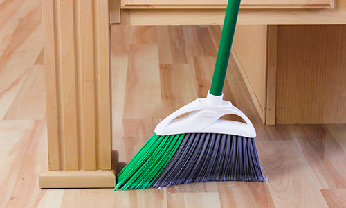 Broom sweeping up crumbs on wood flooring