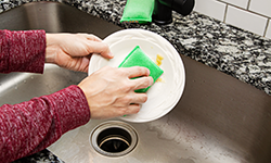 Woman cleaning plate with sponge