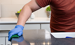 Person wearing nitrile gloves scrubbing counter