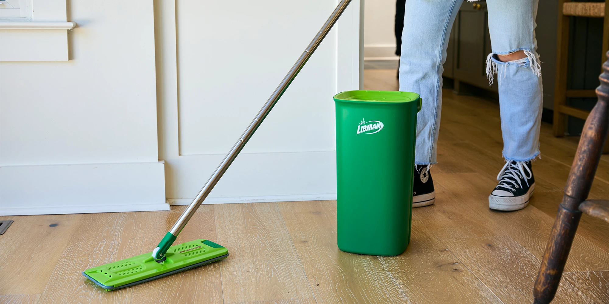 Person cleaning wood floor with flat mop