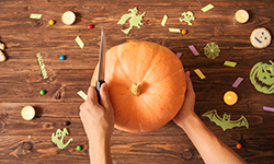 Person cutting off top of pumpkin