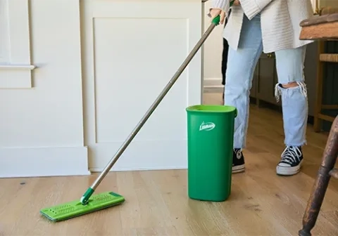 Person cleaning wood floor with flat mop
